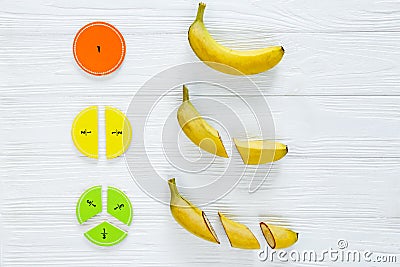 Ð¡olorful math fractions and bananas as a sample on white wooden background or table. Interesting math for kids. Education Stock Photo